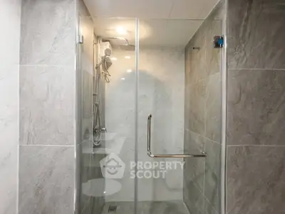 Modern bathroom with sleek glass shower enclosure and elegant marble tiles.