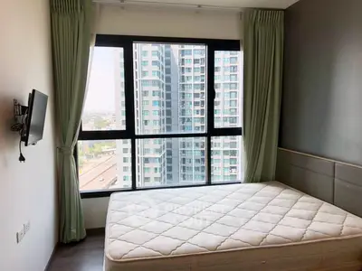Modern bedroom with large window offering stunning city views in high-rise apartment.