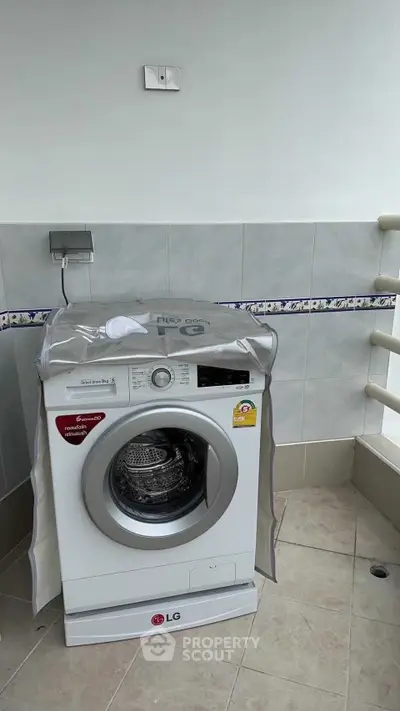 Modern washing machine on tiled balcony with protective cover, ideal for urban apartments.