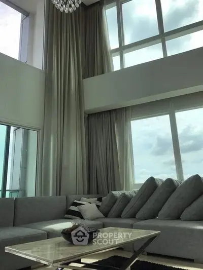 Luxurious high-ceiling living room with large windows and elegant decor