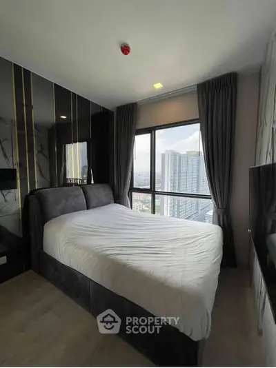 Modern bedroom with large window offering stunning city view in high-rise apartment.