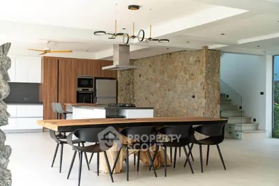 Modern open kitchen with wooden dining table and stone accent wall