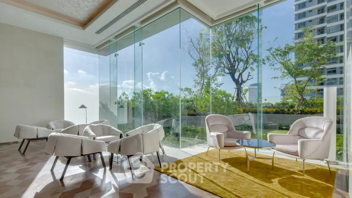 Luxurious modern living room with panoramic glass walls and garden view, featuring elegant white furniture.