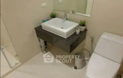 Modern bathroom with sleek sink and toilet, neutral tones and minimalistic design.