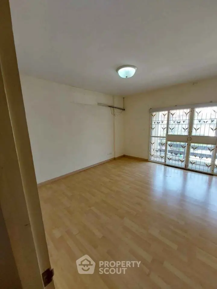 Spacious empty room with wooden flooring and large windows, ideal for customization.