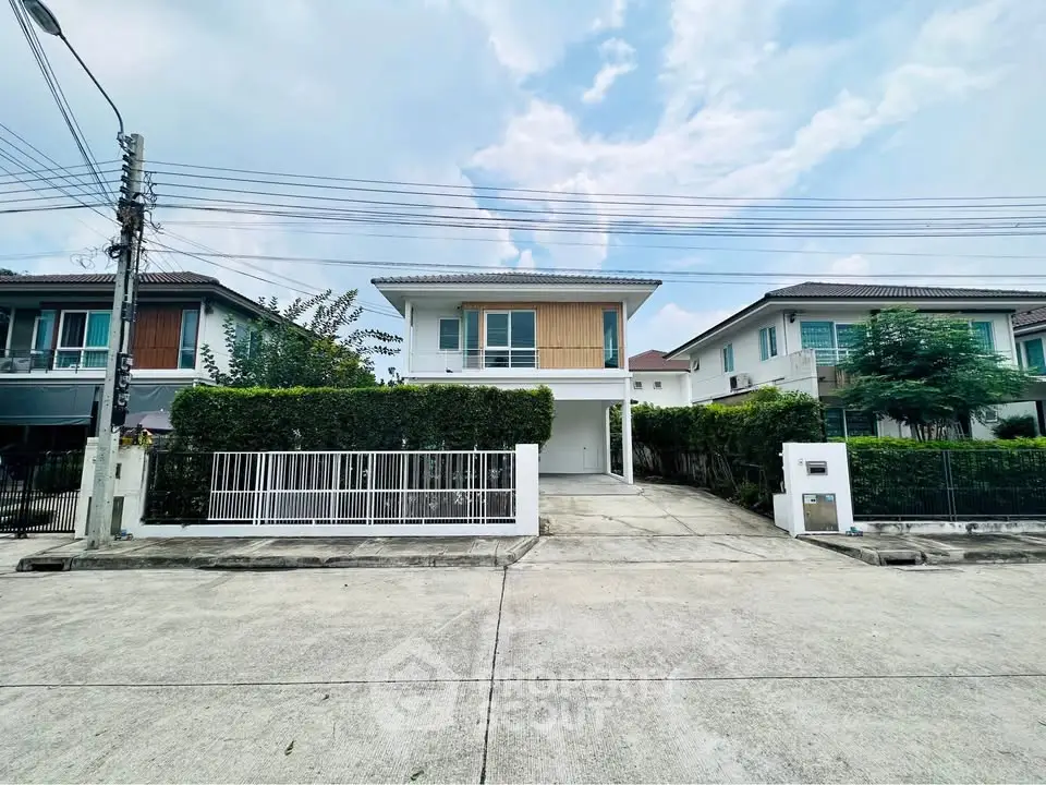 Modern two-story house with spacious driveway and lush greenery in a serene neighborhood.