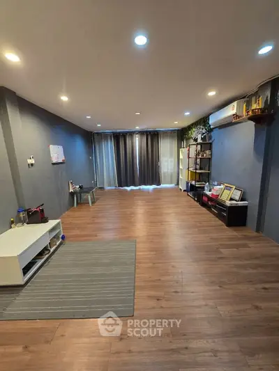 Spacious living room with wooden flooring and modern decor, perfect for relaxation and entertainment.