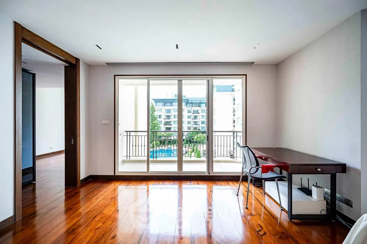 Spacious room with wooden floors and balcony view in modern apartment