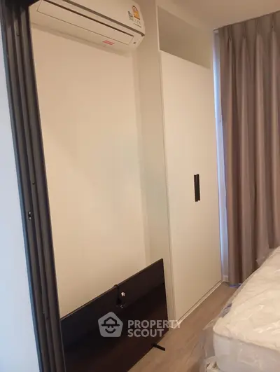 Modern bedroom with sleek wardrobe and air conditioning unit, perfect for comfortable living.