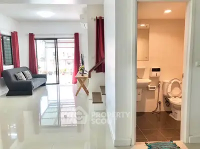 Spacious living room with modern decor and adjacent bathroom in a bright, airy home.