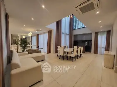 Luxurious open-plan living and dining area with high ceilings and modern decor.