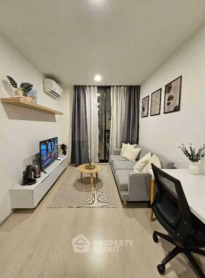 Modern living room with cozy sofa, TV, and stylish decor in a compact apartment.