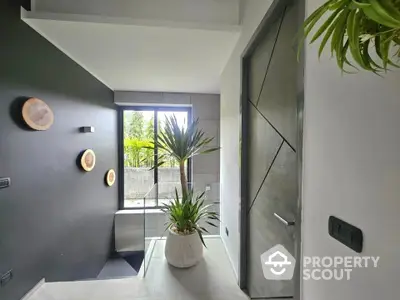 Modern hallway with stylish decor and indoor plants, featuring a sleek design and natural light.