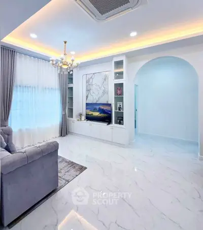 Elegant living room with marble flooring, plush sofa, and modern chandelier in a bright, airy space.