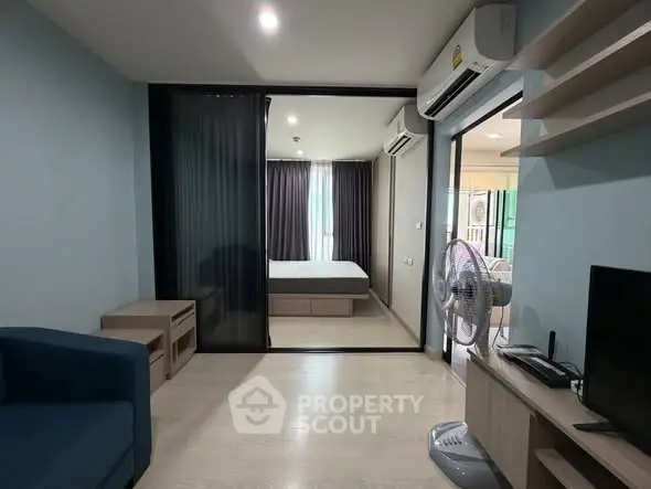 Modern apartment interior with open living room and bedroom layout, featuring sleek furniture and natural light.