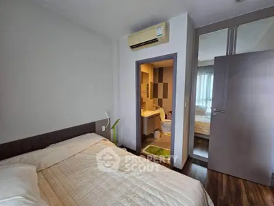 Cozy bedroom with ensuite bathroom and mirrored closet doors in modern apartment.