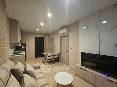 Modern living room with open kitchen, stylish decor, and cozy seating area.