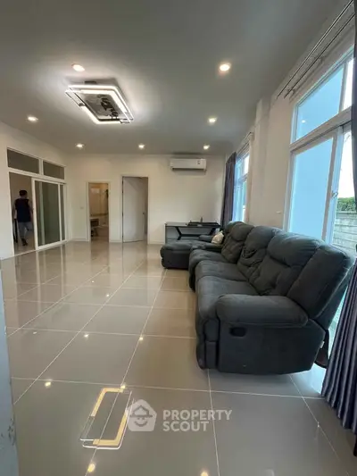 Spacious modern living room with sleek tile flooring and large windows for natural light.