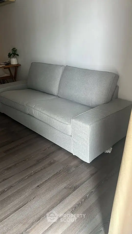 Modern living room with sleek gray sofa and stylish wooden flooring.