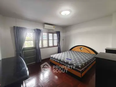 Spacious bedroom with large window and modern furnishings in a well-lit apartment.