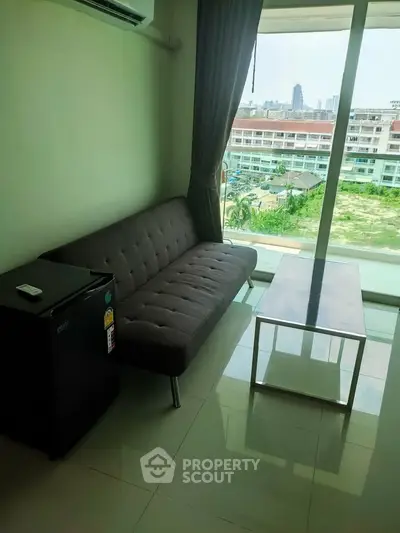 Modern living room with city view, featuring a sleek sofa and glass coffee table.