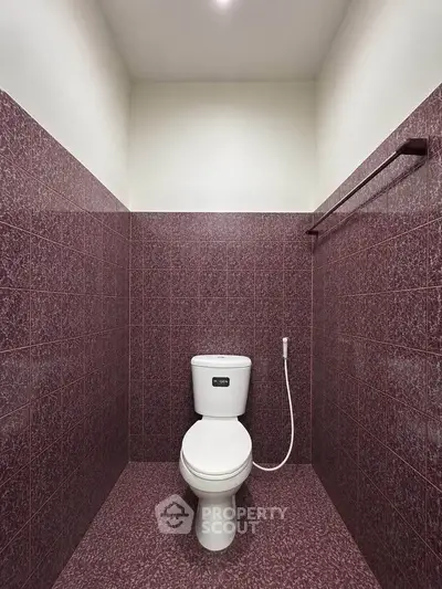Modern bathroom with unique maroon tile design and sleek toilet fixture.