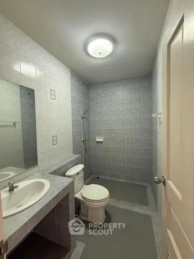 Spacious bathroom with modern fixtures and tiled walls, featuring a shower and toilet.