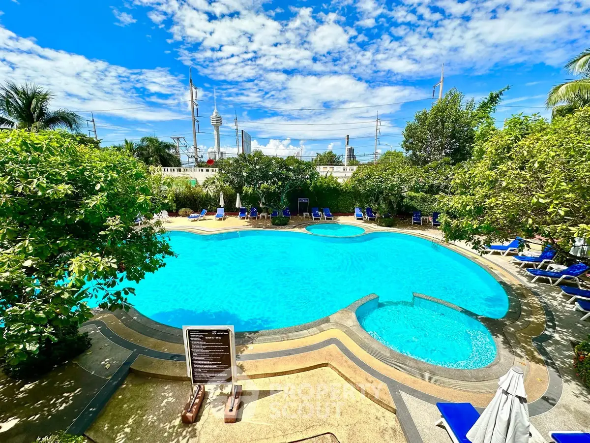 Luxurious outdoor pool with lush greenery and clear blue skies, perfect for relaxation.