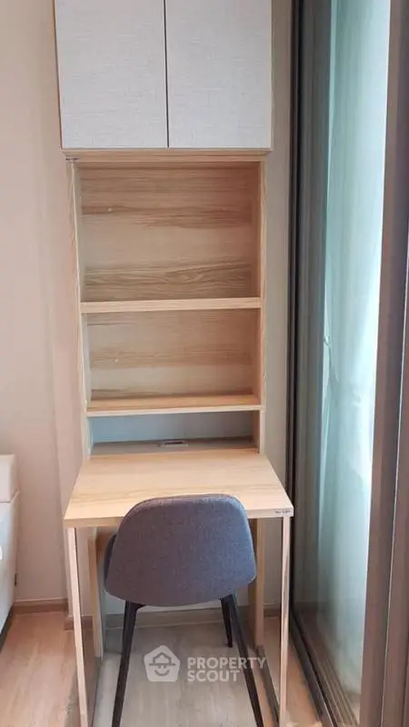 Compact study nook with wooden desk and chair by a window, perfect for focused work.