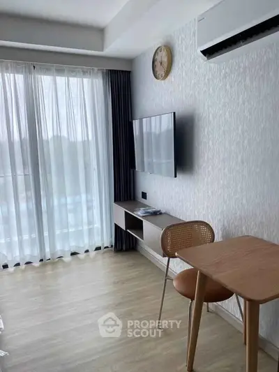Modern living room with wall-mounted TV and air conditioning, featuring a stylish wooden table and chair.