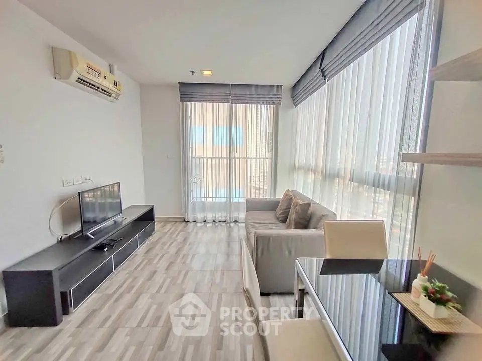 Modern living room with large windows and stylish furniture in a high-rise apartment.