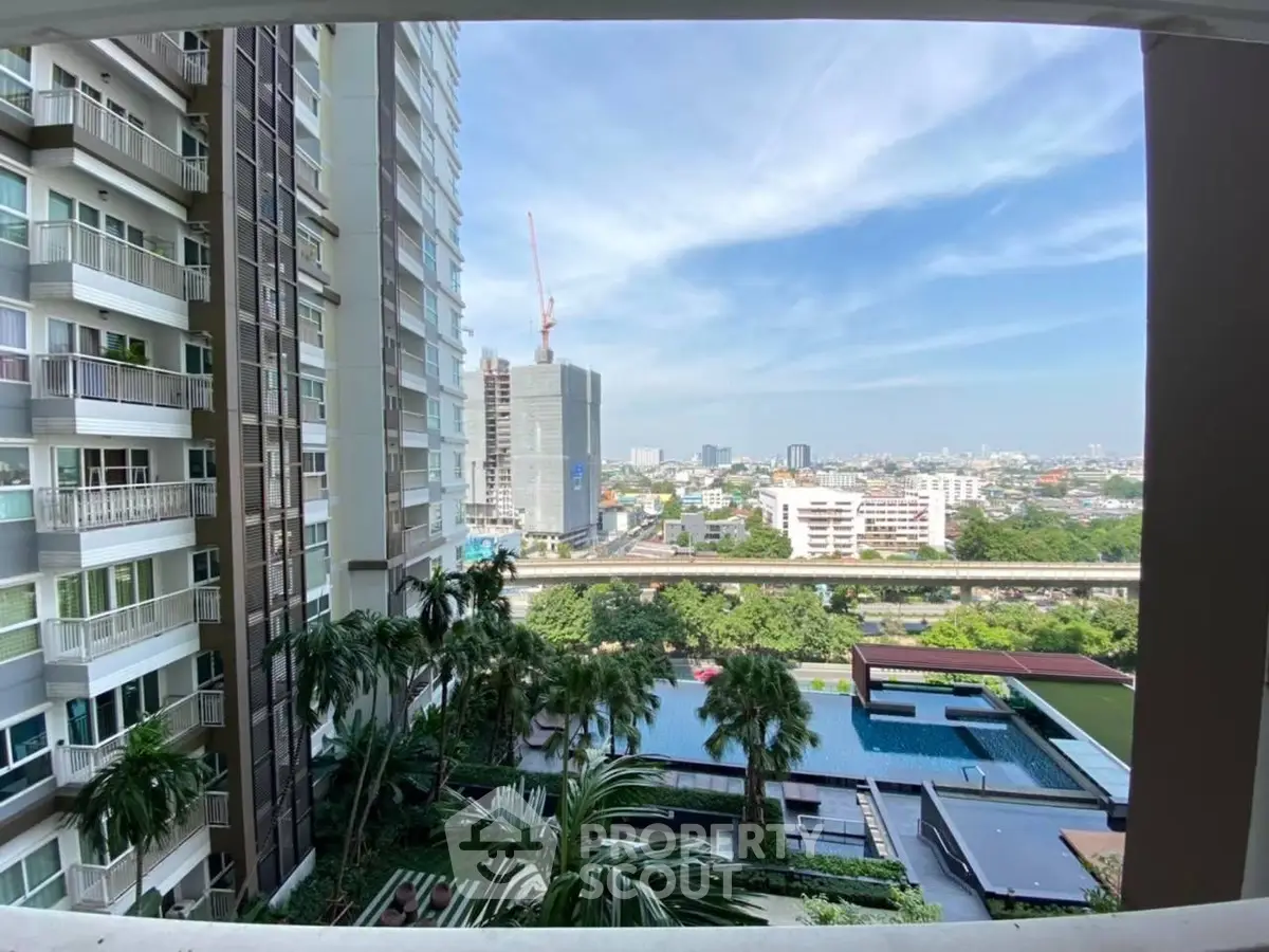 Stunning city view from a modern high-rise balcony overlooking a lush pool area.