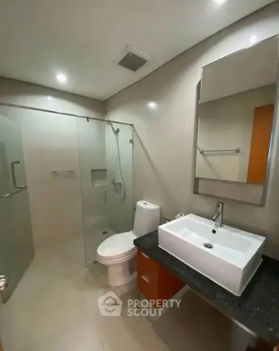 Modern bathroom with glass shower and sleek vanity in contemporary home.