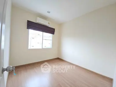 Spacious empty bedroom with wooden flooring and air conditioning
