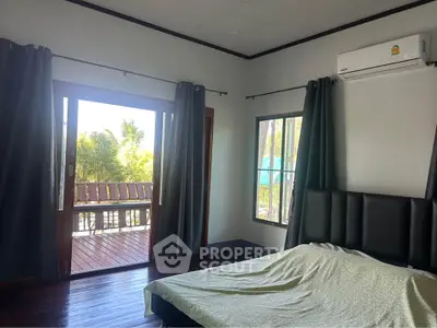 Spacious bedroom with balcony access and air conditioning, offering serene views and natural light.