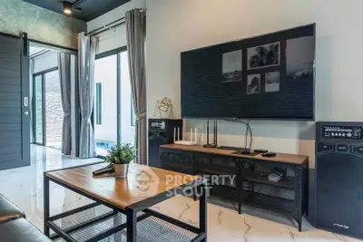 Modern living room with sleek decor, large TV, and stylish furniture, offering a glimpse of outdoor pool area.