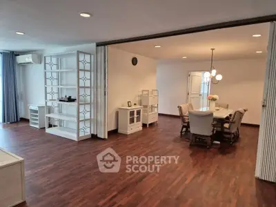 Spacious open-plan living and dining area with elegant wooden flooring and modern furnishings.