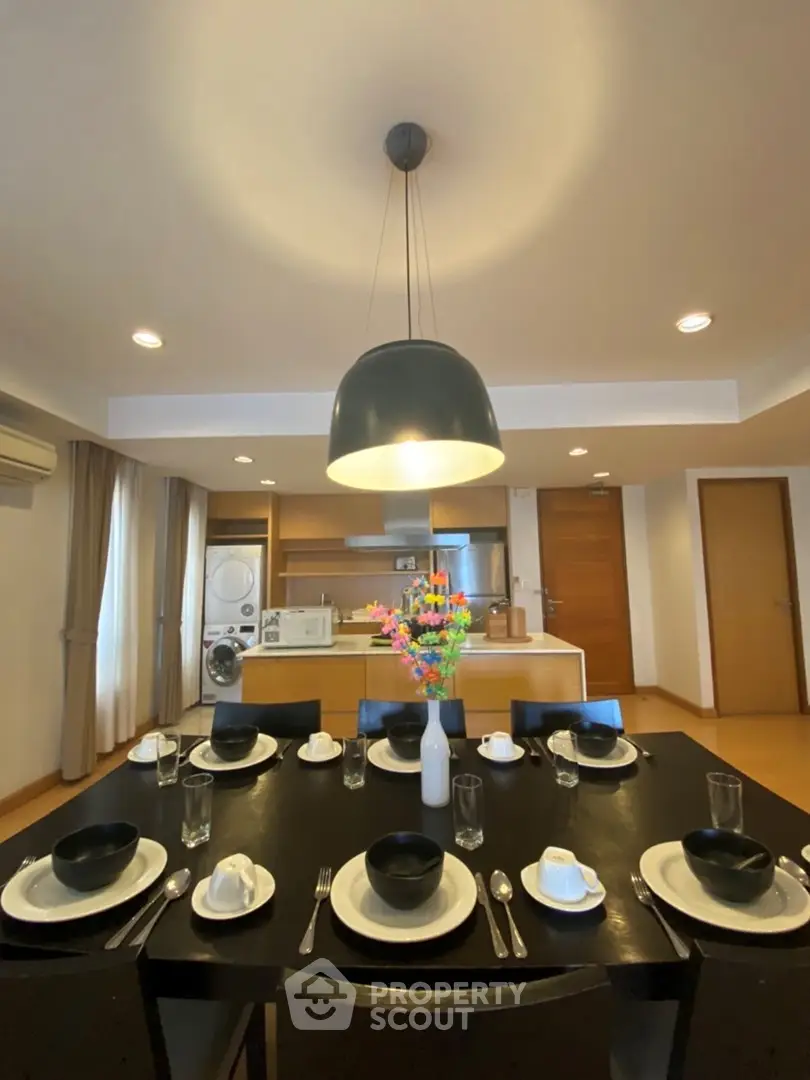 Spacious dining area with modern kitchen and elegant table setting in a stylish apartment.