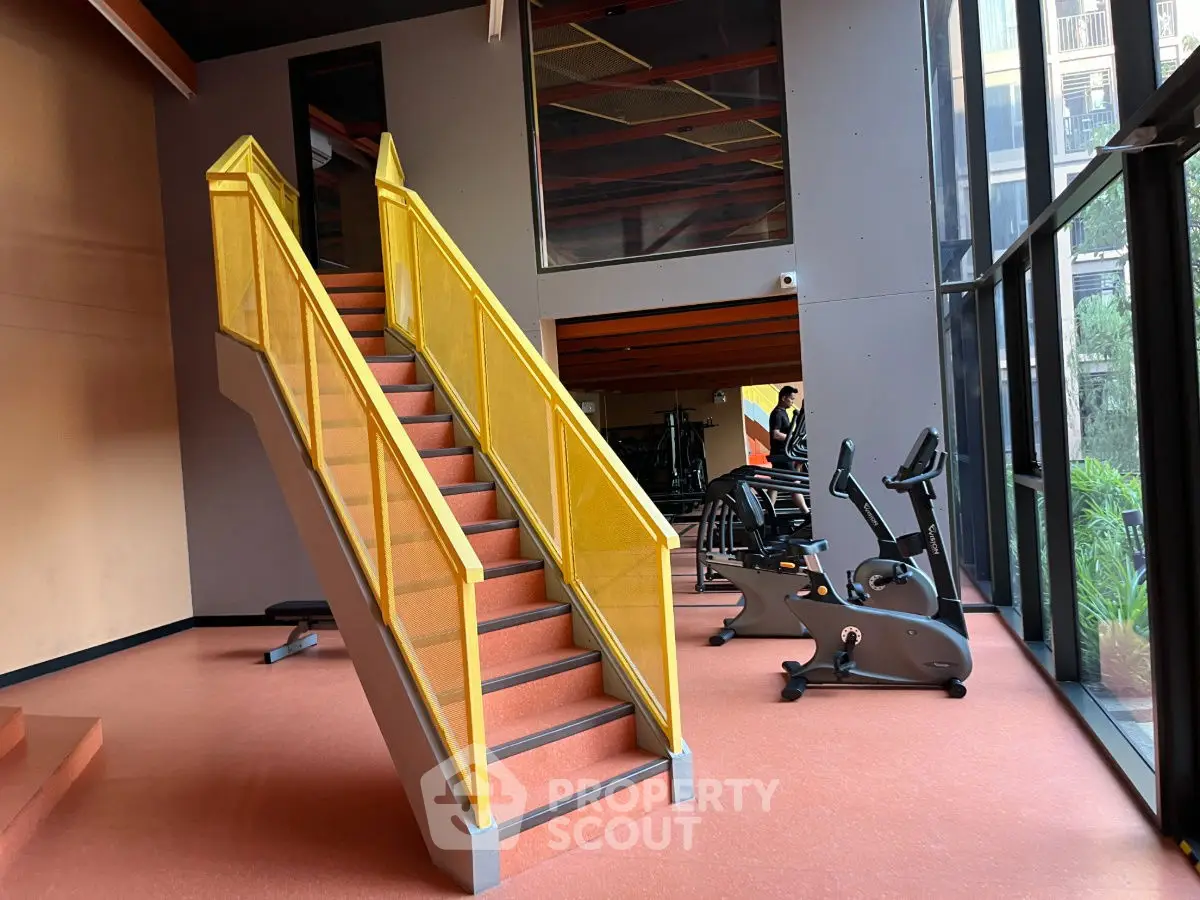Modern gym with bright yellow staircase and exercise bikes