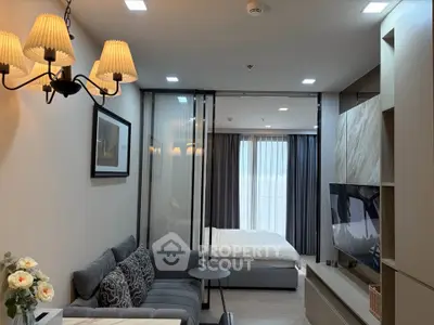 Modern studio apartment with cozy living area and elegant bedroom separated by glass partition.