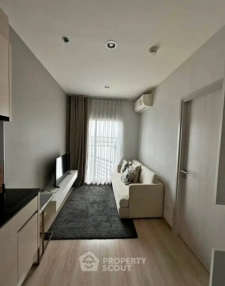 Modern living room with sleek design, featuring a cozy sofa, flat-screen TV, and natural light from large window.