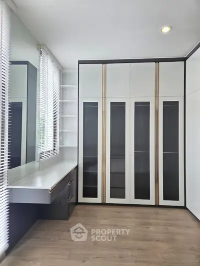 Modern bedroom with sleek built-in wardrobe and large window for natural light.
