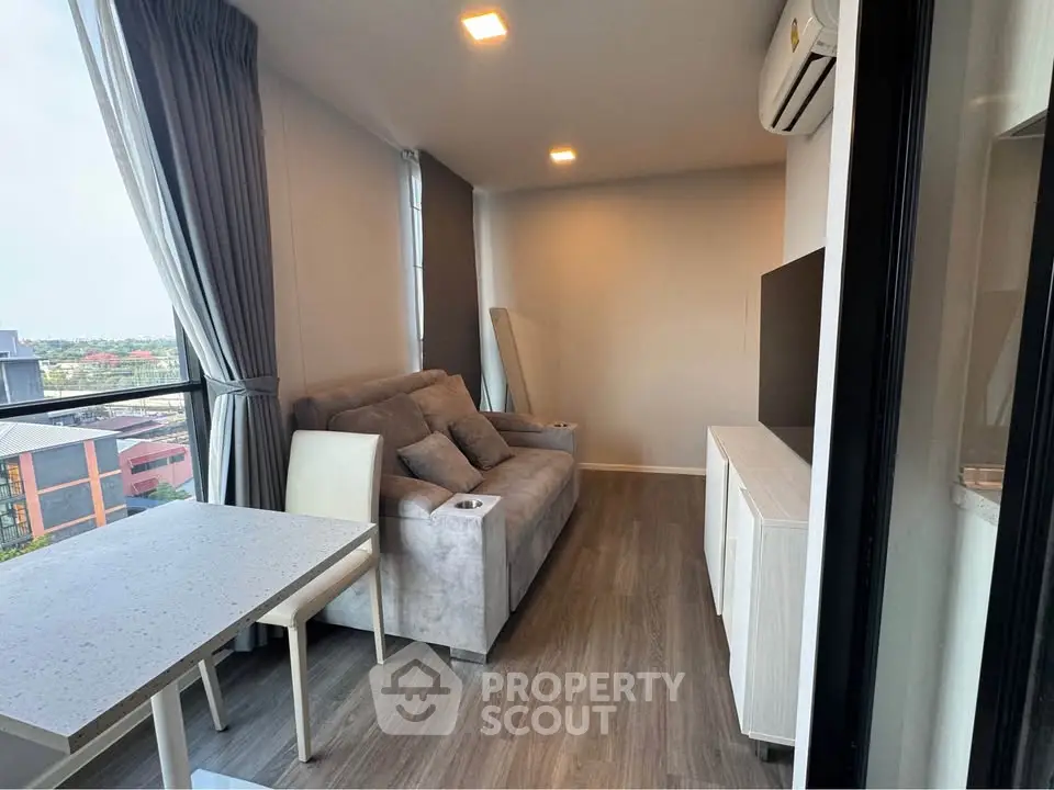 Modern living room with cozy sofa, air conditioning, and large windows offering city views.