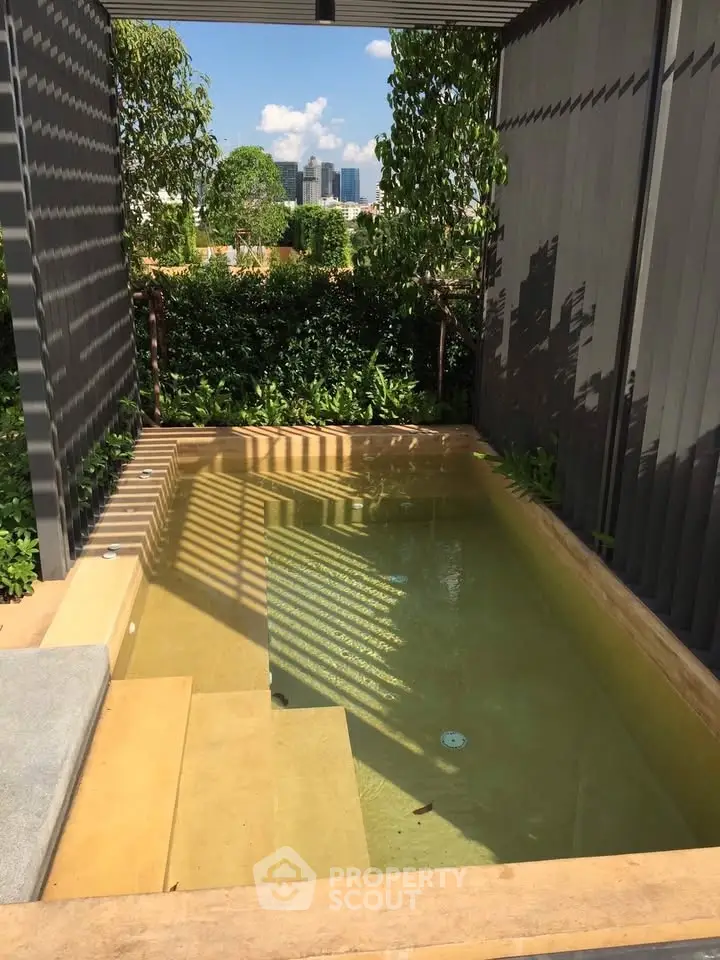 Charming private plunge pool with lush greenery and city skyline view, perfect for relaxation and luxury living.