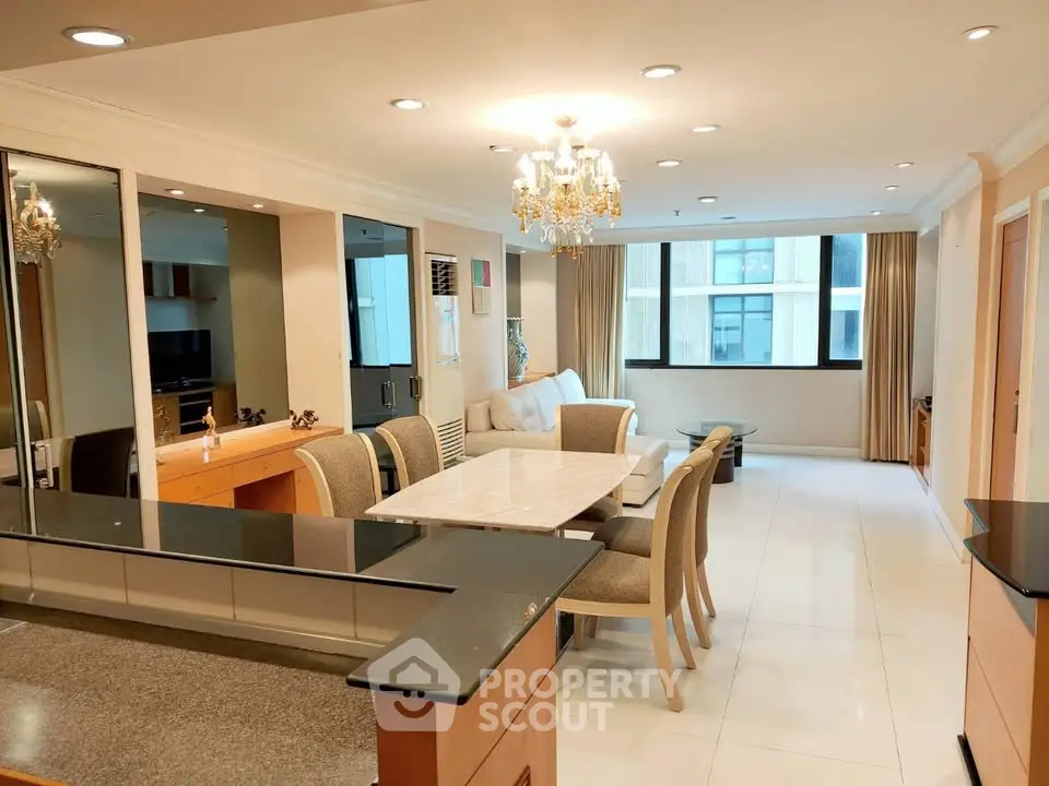 Elegant open-plan living and dining area with chandelier and large windows in modern apartment.
