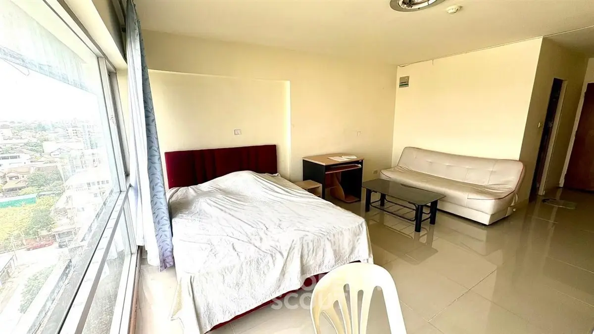 Spacious bedroom with large window offering city views, modern furnishings, and ample natural light.