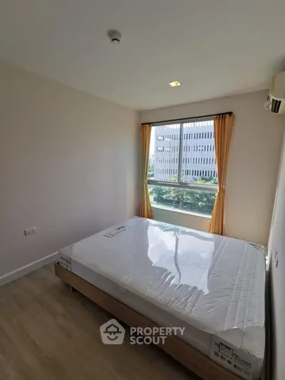 Bright bedroom with large window and new mattress in modern apartment