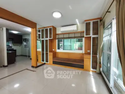 Spacious modern living room with large windows and built-in seating, featuring sleek wooden accents and ample natural light.