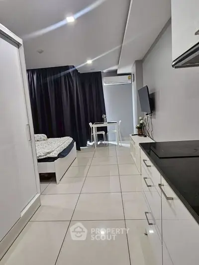 Modern studio apartment with sleek design, featuring a cozy bed, compact dining area, and efficient kitchen setup.