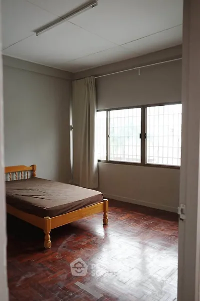 Cozy bedroom with wooden bed frame and large window, perfect for natural light lovers.